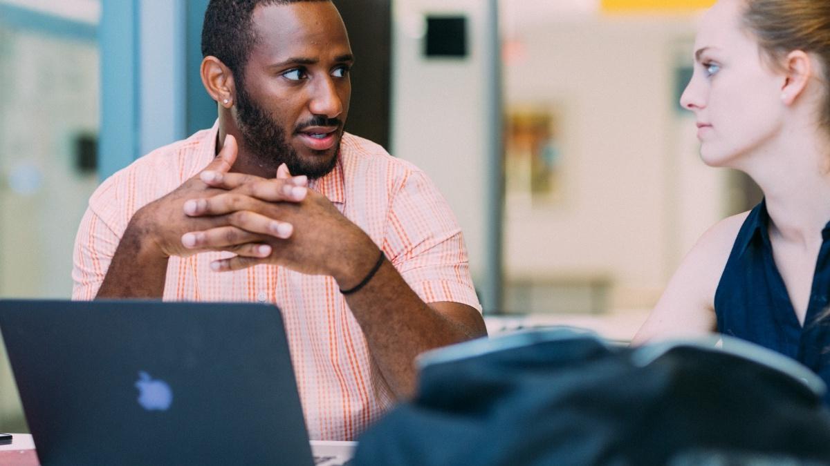 Two students at laptops having a discussion